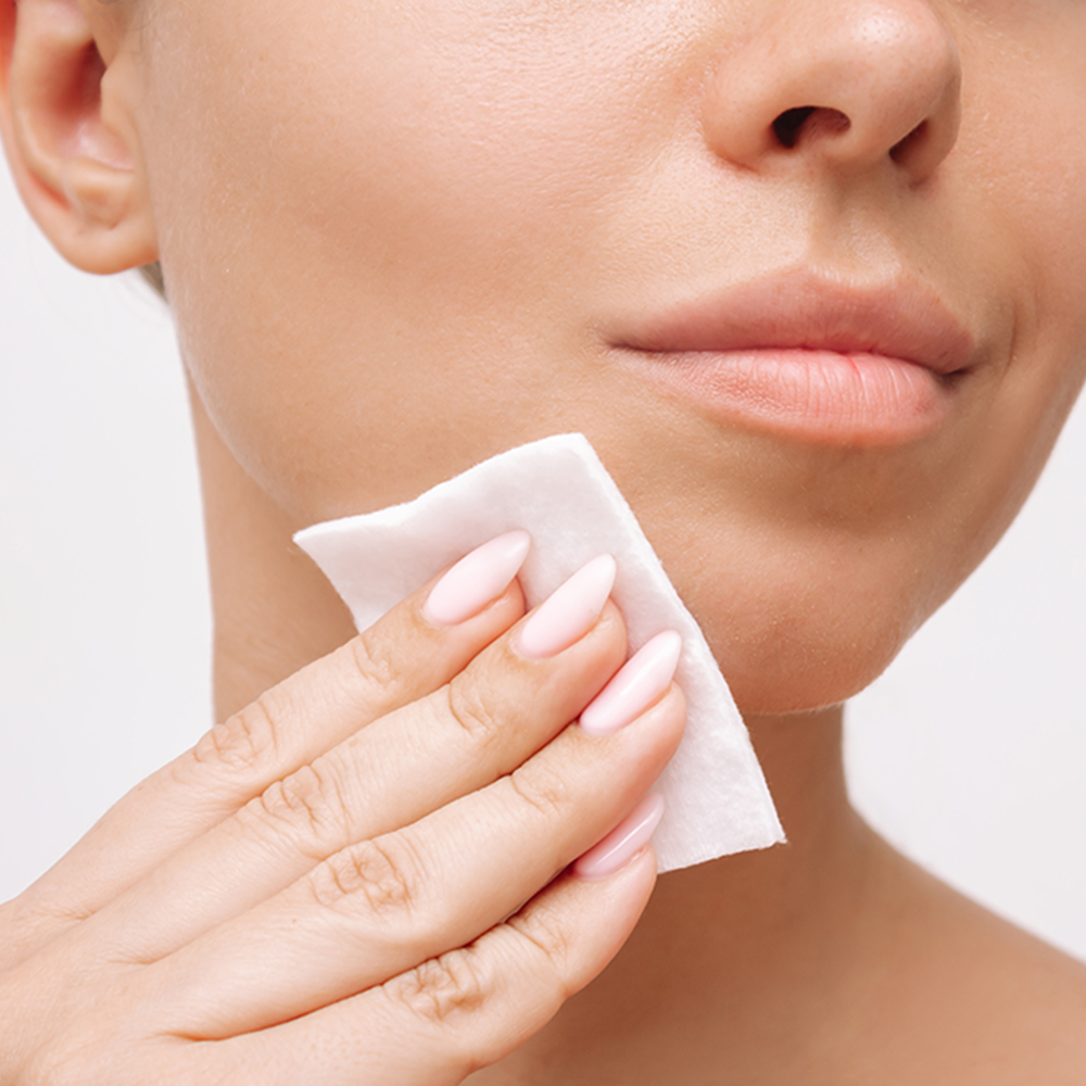 Main d'une femme qui passe un coton sur le visage