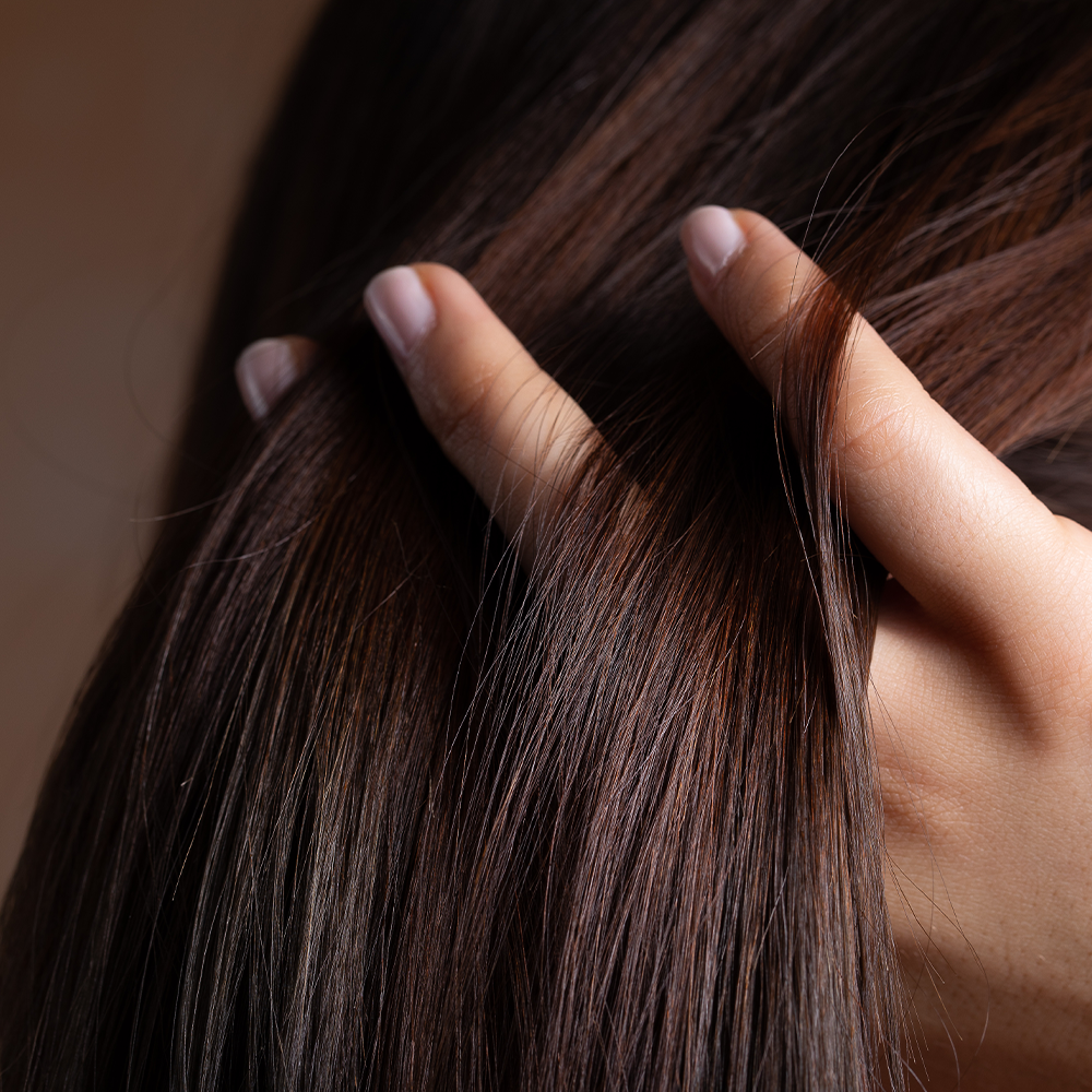 Main de femme dans de longs cheveux bruns brillants