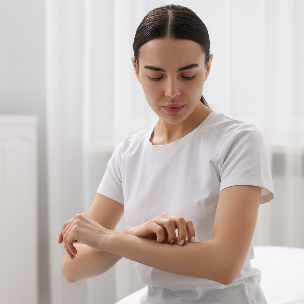 Une femme se gratte le bras