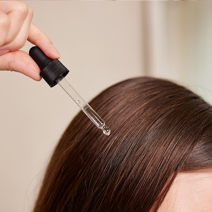 Pipette avec une goutte qui tombe sur les cheveux