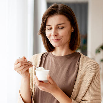 Une femme mange un yaourt