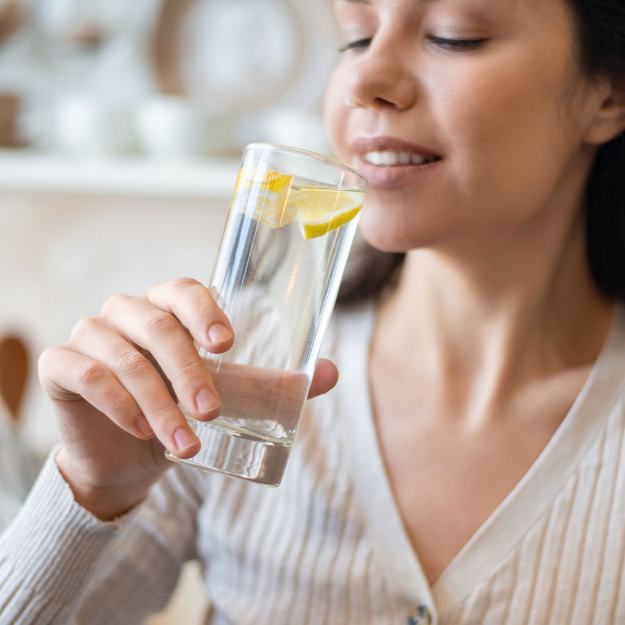 Jeune femme qui s'apprête à boire un grand verre d'eau avec du citron dedans